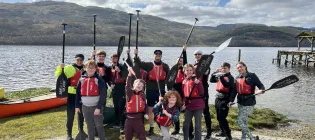 Aaron Kelly and Boys Brigade posing with paddles by a loch