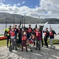 Aaron Kelly and Boys Brigade posing with paddles by a loch. Staff volunteering.