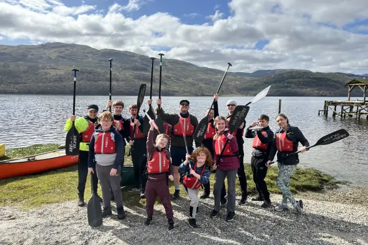 Aaron Kelly and Boys Brigade posing with paddles by a loch. Staff volunteering.