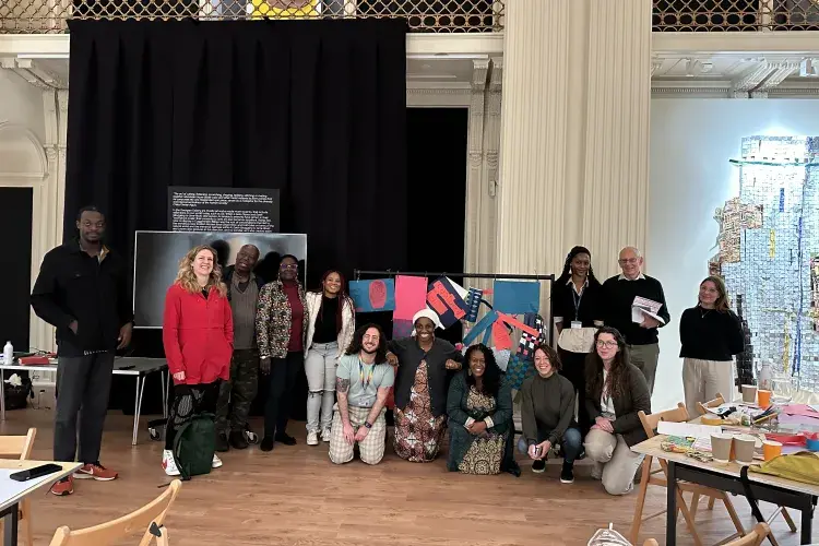 A goup of participants from a Decolonised Transformations workshop are posing for the camera. They are inside the Talbot Rice Gallery and are a mixture of ethnicities, genders and age groups.. 