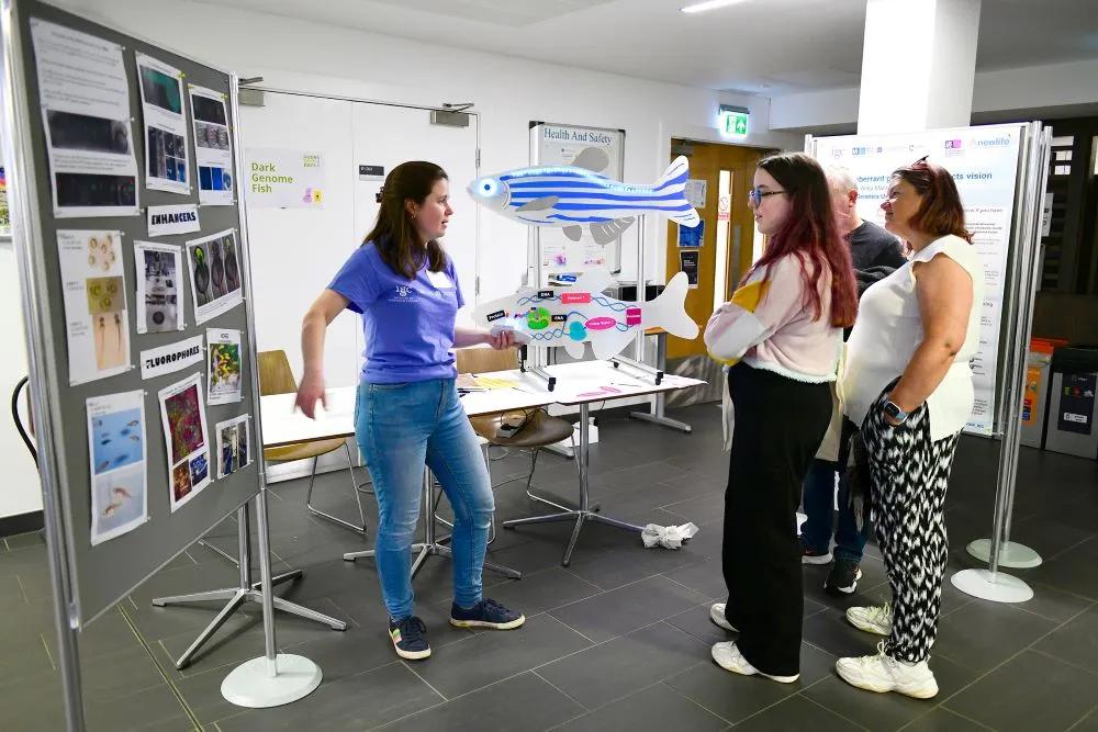 Researcher talking to visitors at the Institute for Genetics and Cancer.
