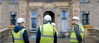 Group in high vis jackets entering building "I was a stranger and ye took me in" over the threshold.