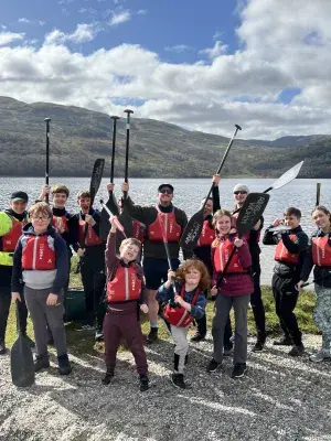 Aaron Kelly and Boys Brigade posing with paddles by a loch. Staff volunteering.