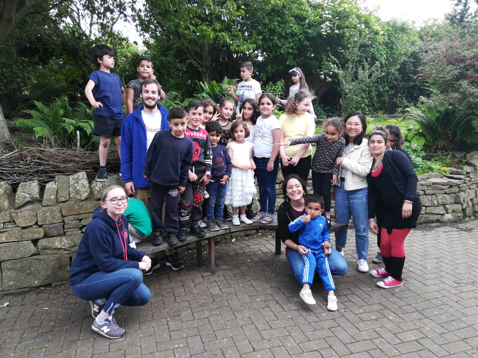 Image shows group of children and student volunteers posing for a photo outdoors